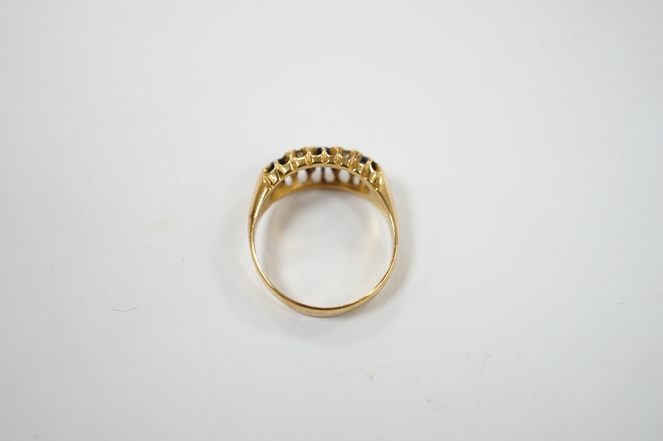 An early 20th century yellow metal, three stone sapphire and four stone diamond chip set half hoop ring, size P, gross weight 4.7 grams.